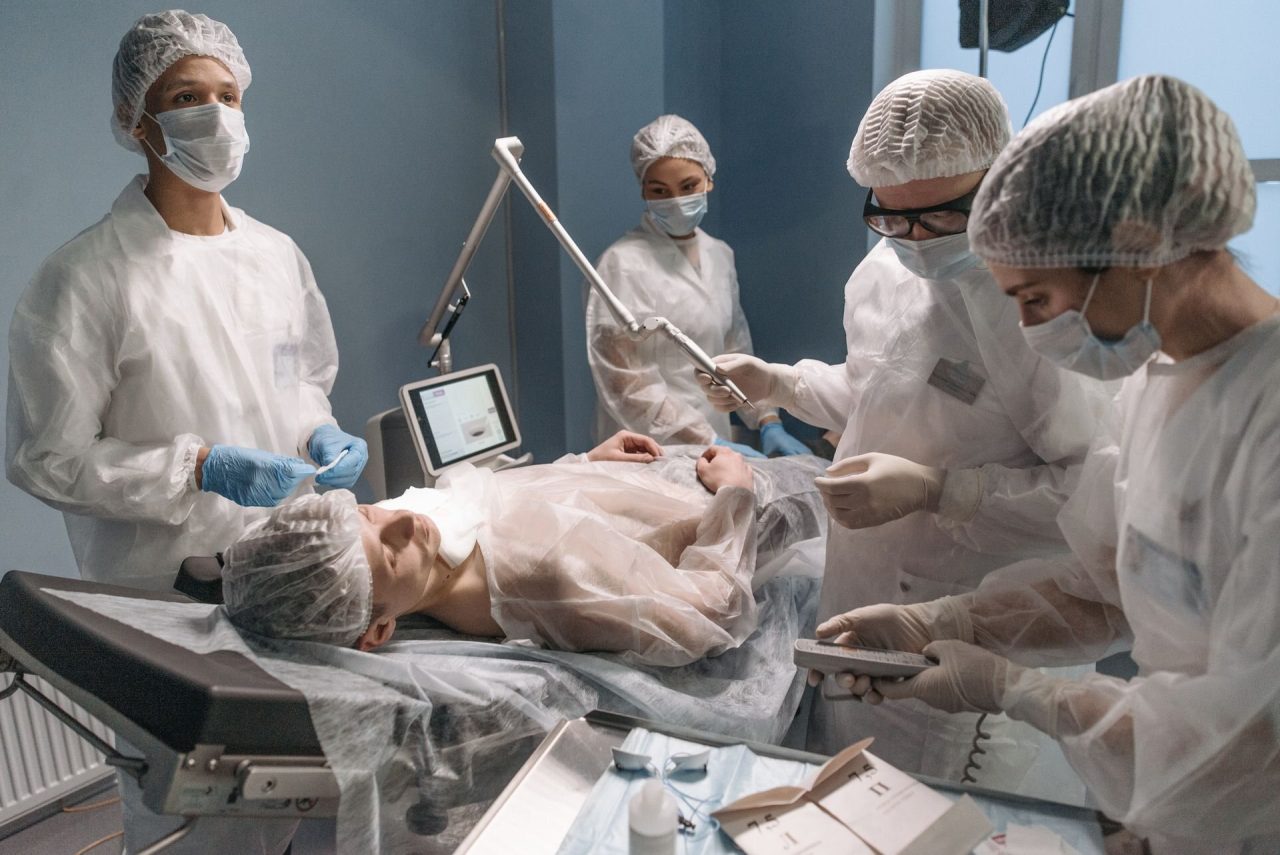 An operating theatre team in caps and gowns working around a patient under anaesthesia