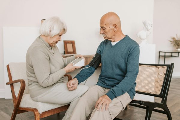 An older couple checking blood pressure at home, part of monitoring heart health